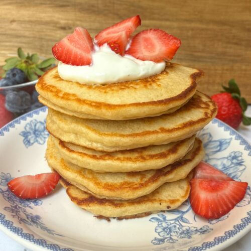 A stack of eggless protein pancakes with greek yogurt and strawberries on top
