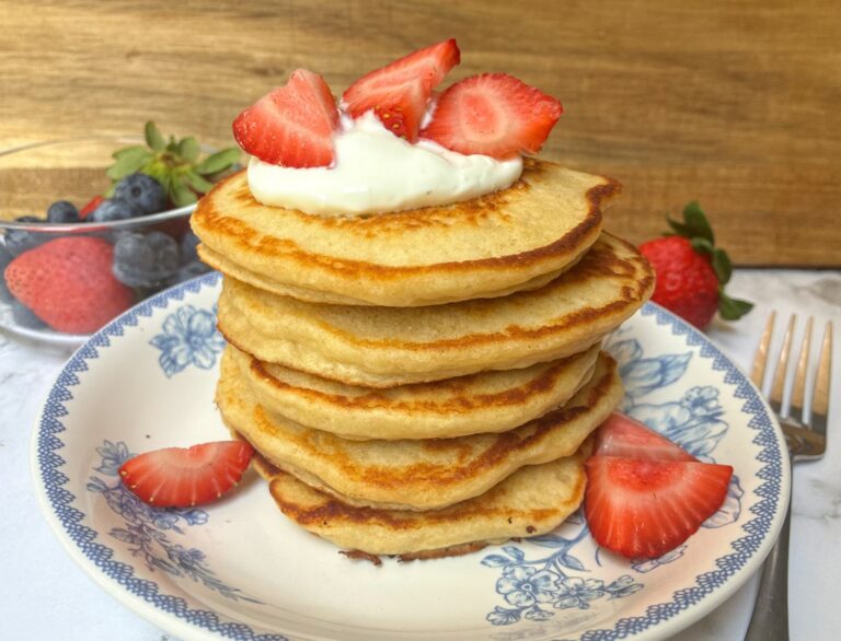 A stack of eggless protein pancakes with greek yogurt and strawberries on top