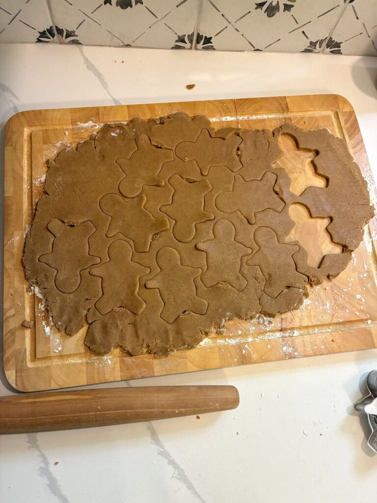 gingerbread men cookies being cut out of dough