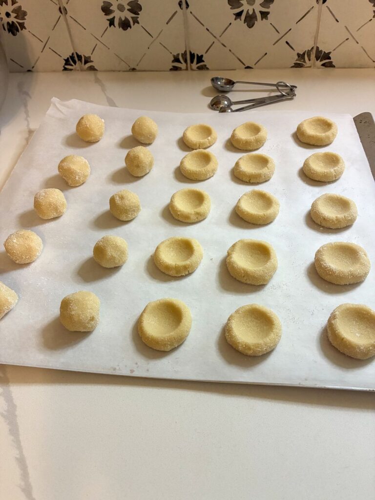 eggless thumbprint cookies with an indent on them on a baking sheet
