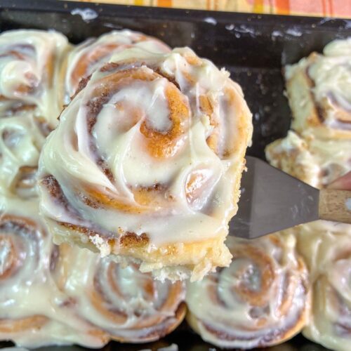 eggless cinnamon rolls being scooped out of the pan