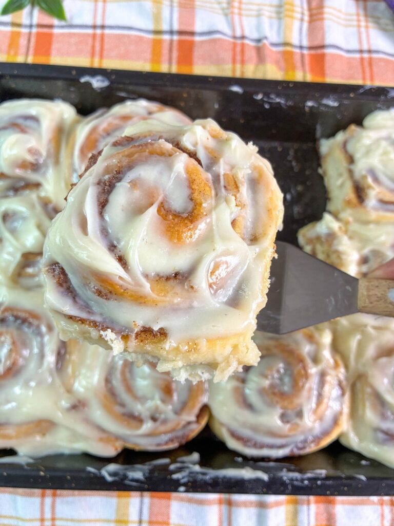 eggless cinnamon rolls being scooped out of the pan