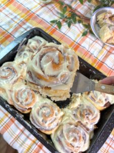 eggless cinnamon rolls being scooped out a pan