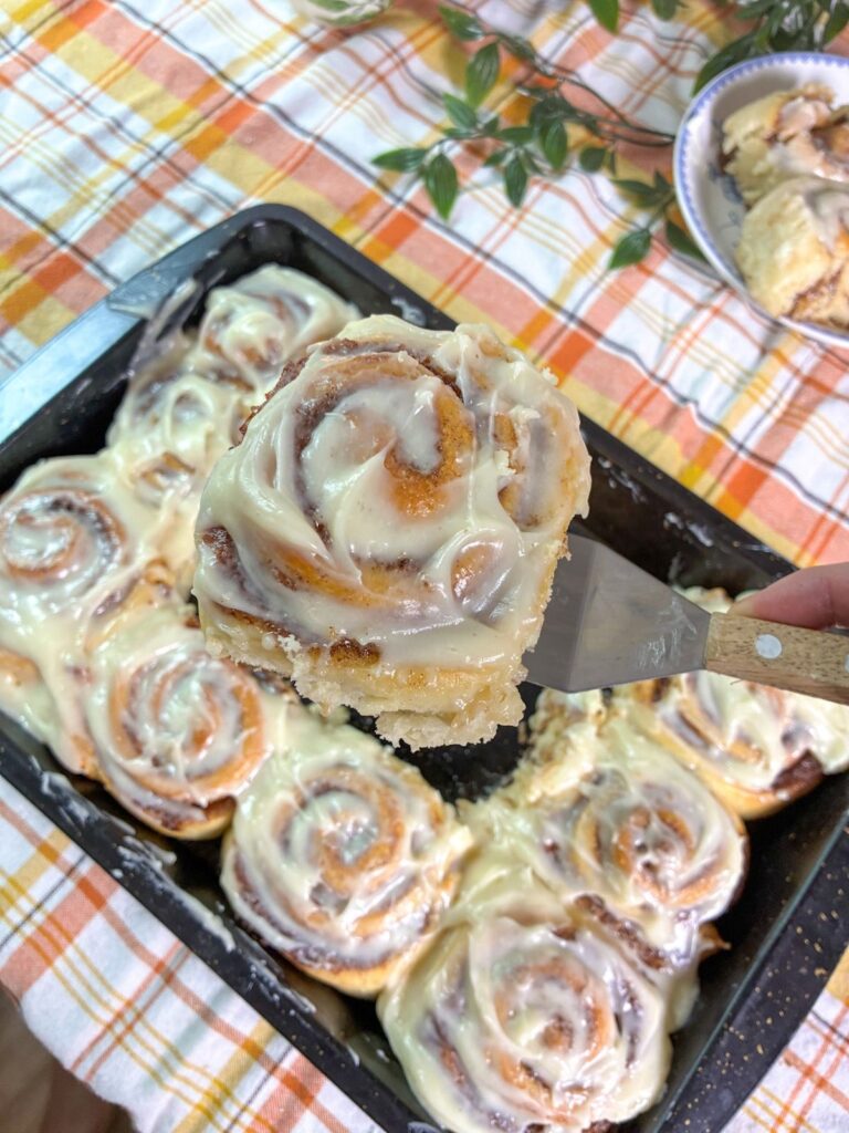 eggless cinnamon rolls being scooped out a pan