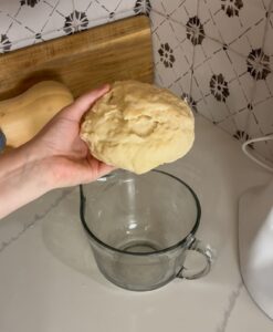 eggless cinnamon roll dough being held by a hand