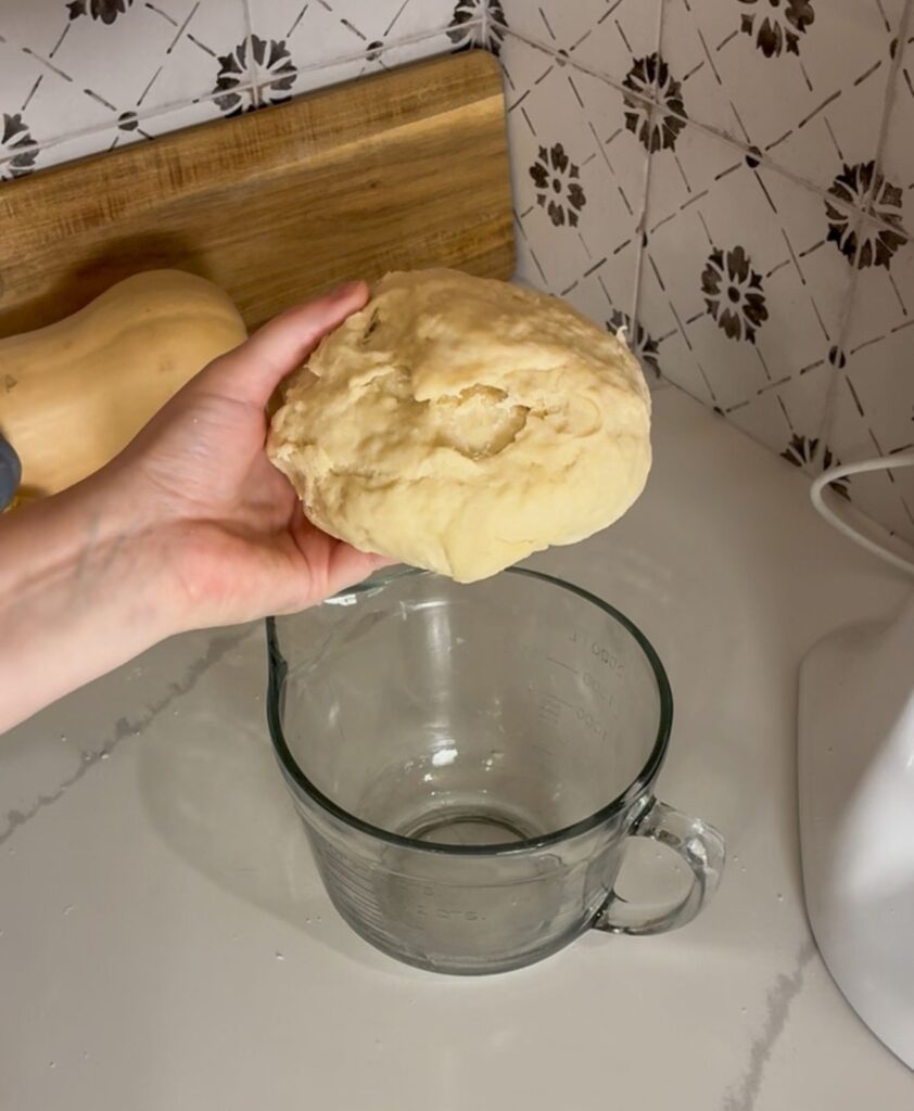 eggless cinnamon roll dough being held by a hand